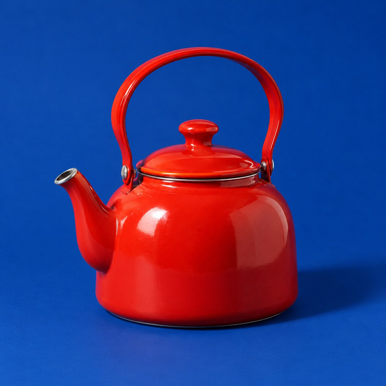 A vermilion enamel kettle on a deep blue backdrop