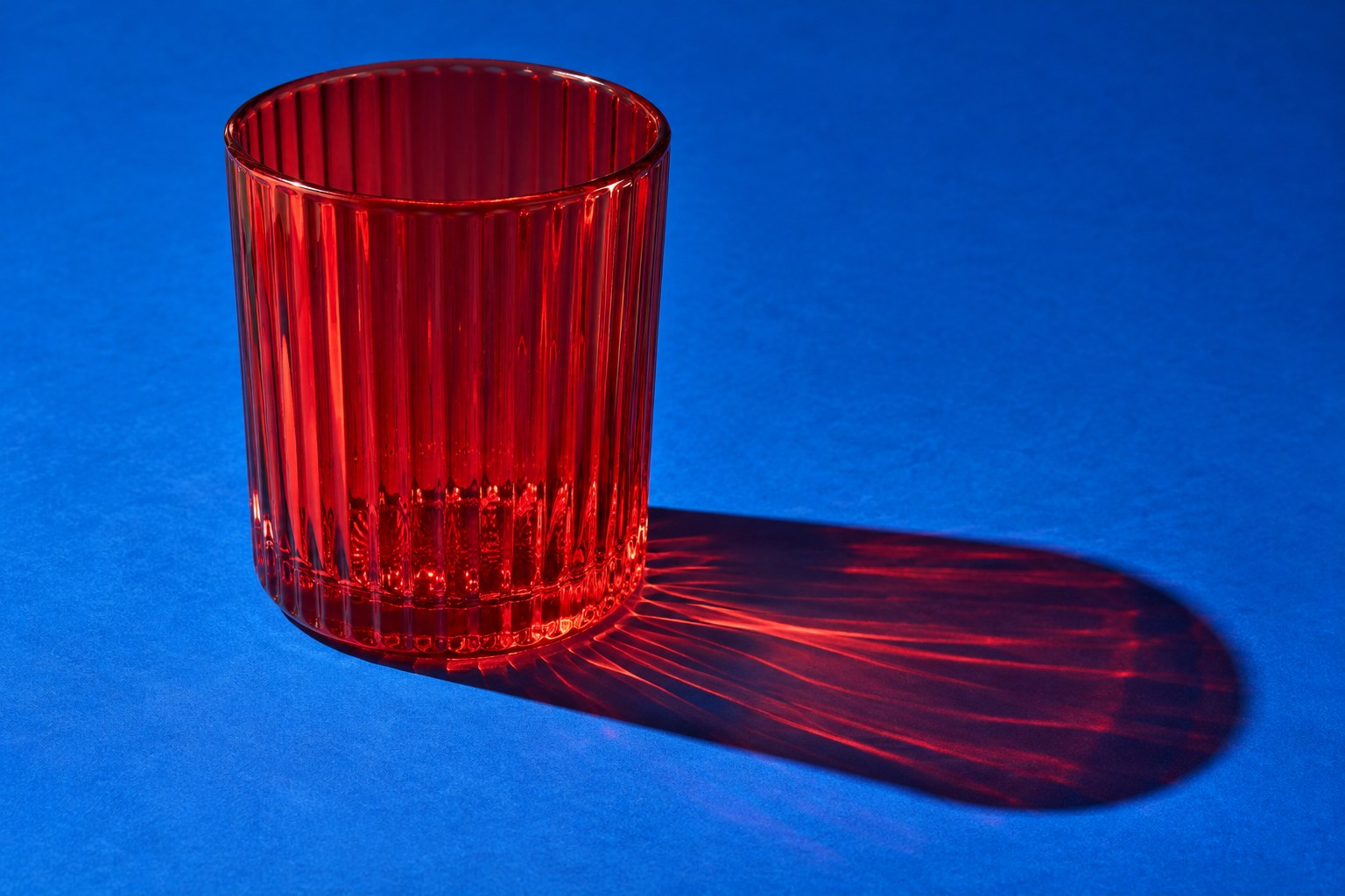 Red ribbed glass casting colored light on cobalt paper