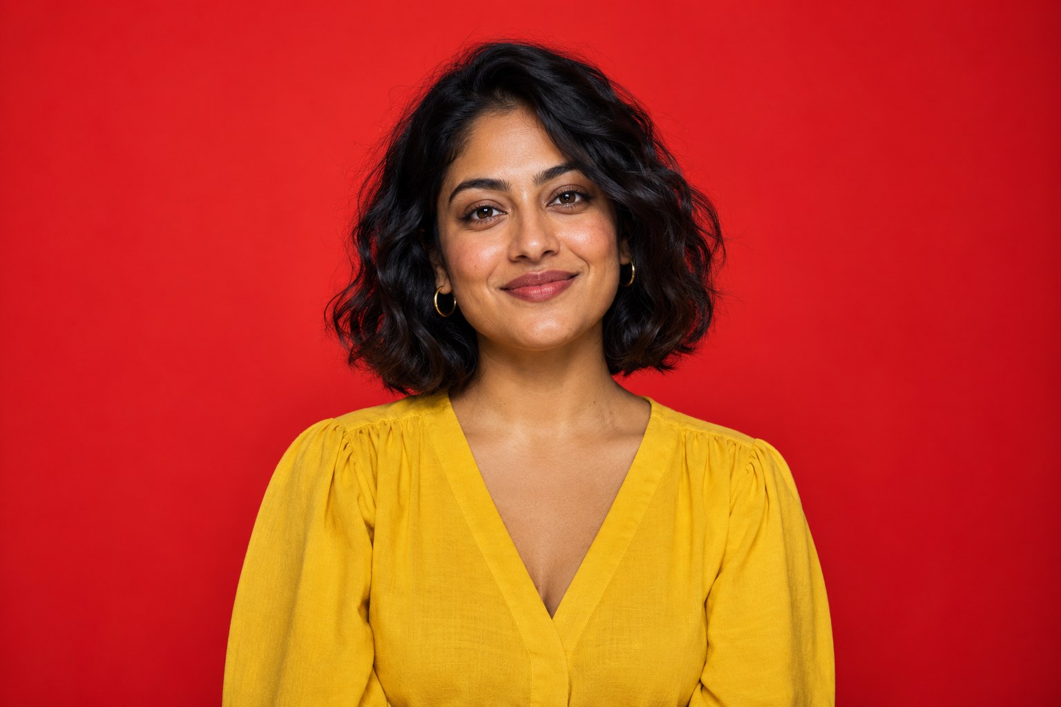A woman with a wavy bob wearing marigold against vermilion