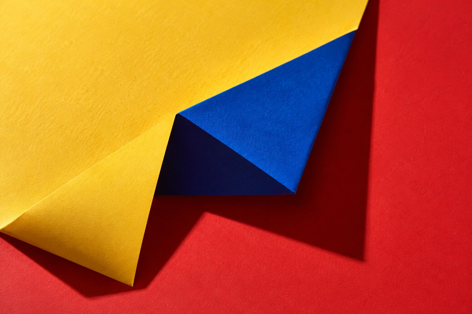 Folded marigold and cobalt paper on a vermilion surface