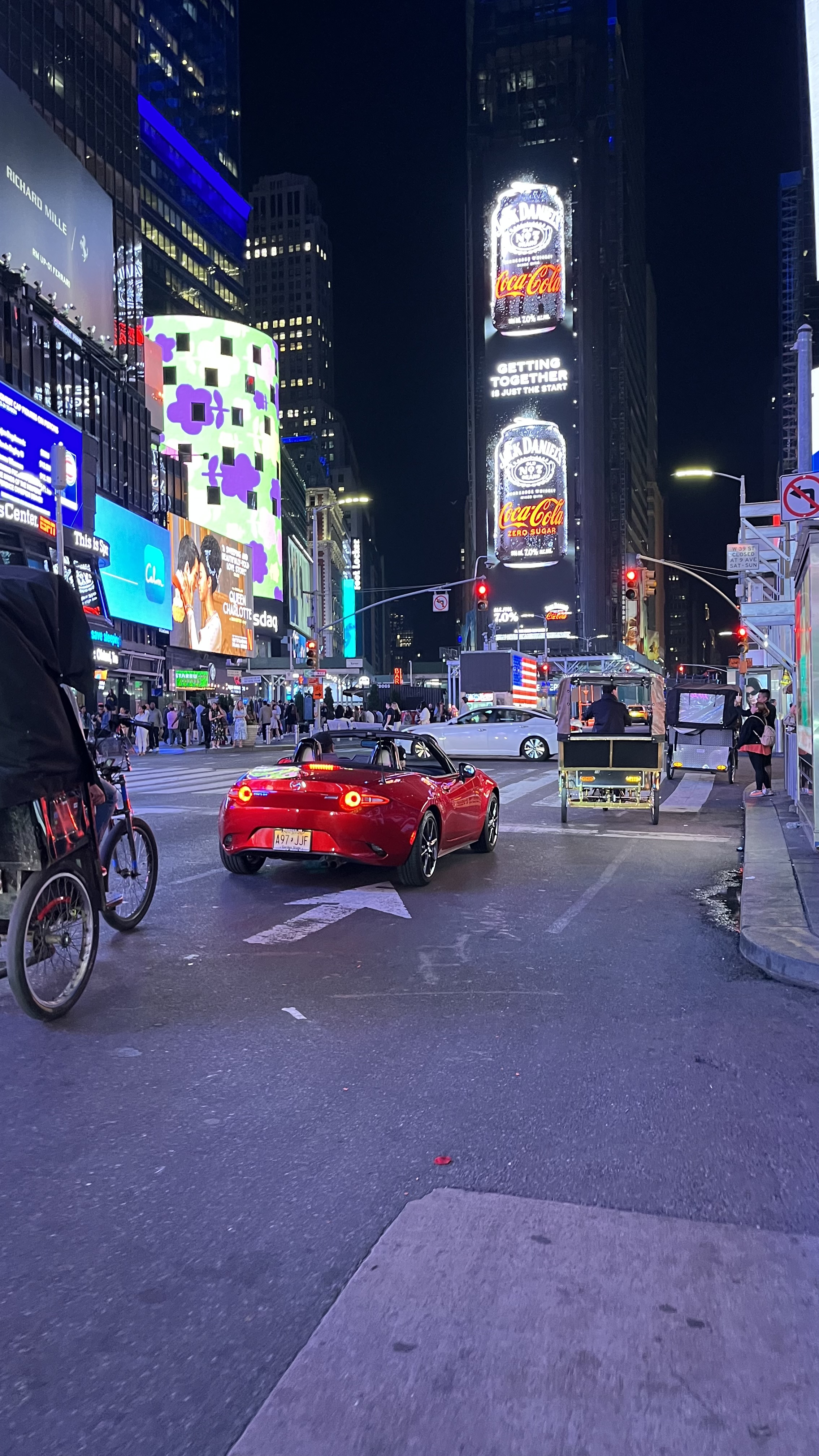 Times Square at night with a red convertible.