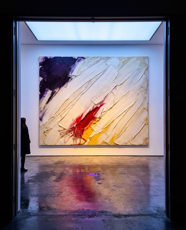 A large impasto painting in a bright gallery, one visitor watching, made by Muse.