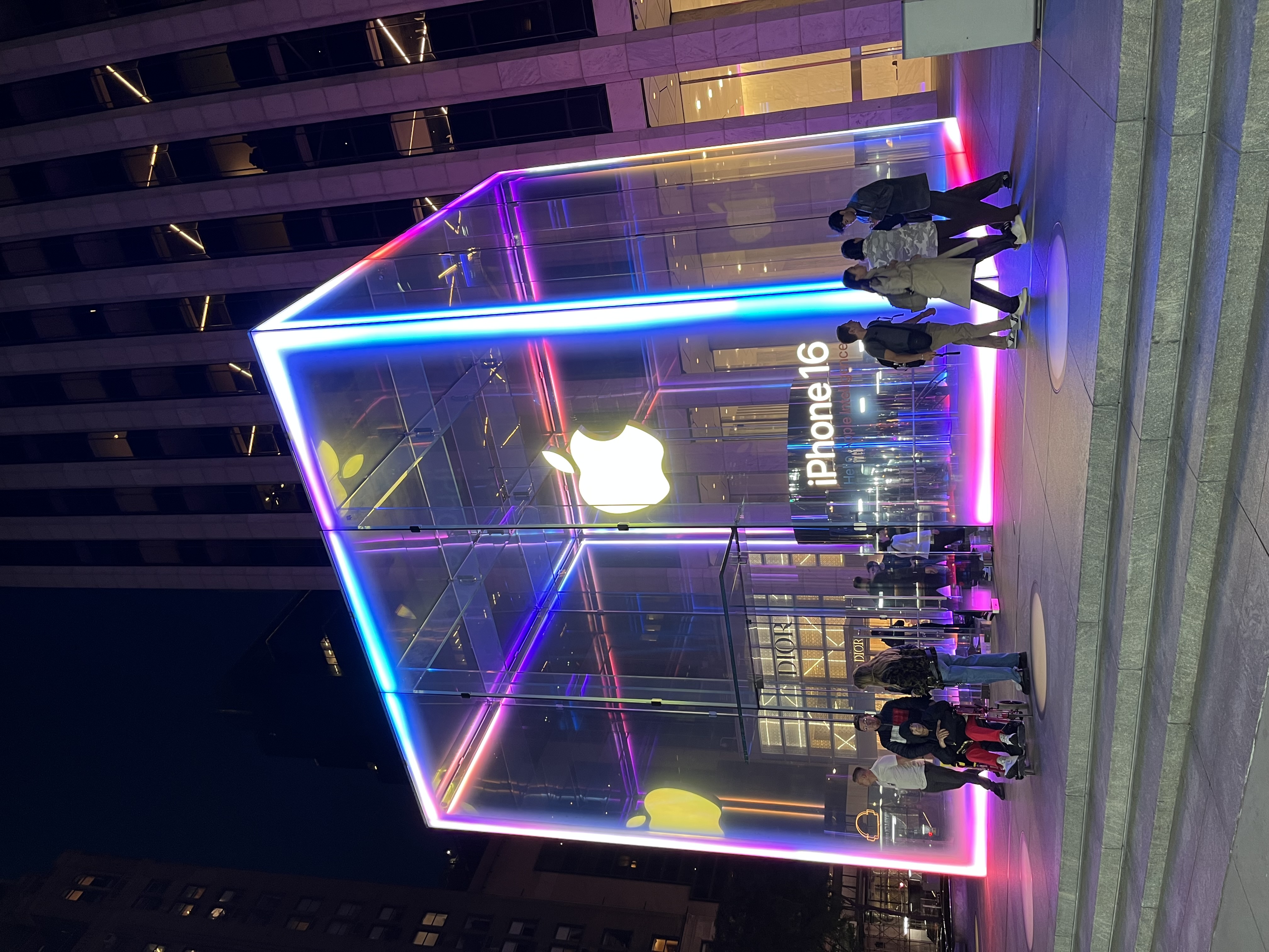A glowing glass cube storefront at night.